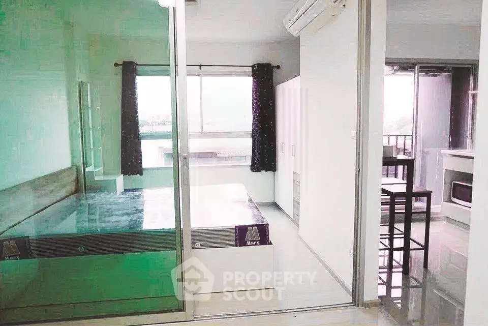 Modern apartment with glass partition, cozy bedroom, and sleek kitchen area.
