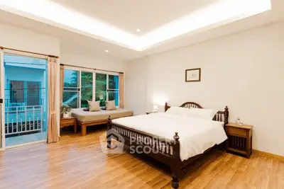 Spacious bedroom with elegant wooden flooring and cozy seating area.