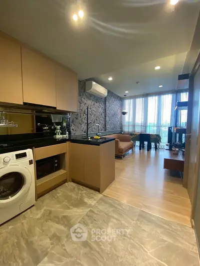 Modern open-layout kitchen and living room with stylish decor and natural light.