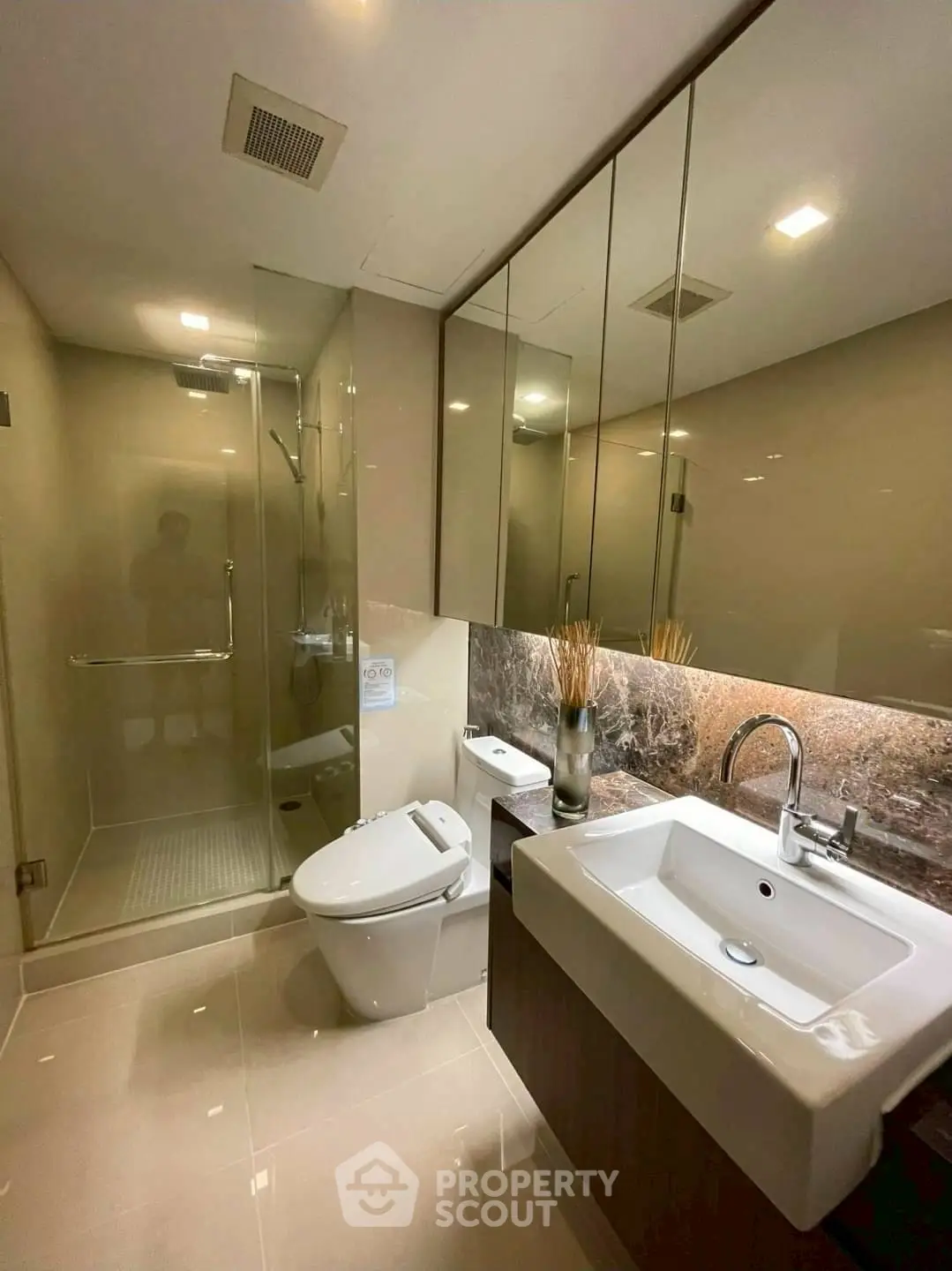 Modern bathroom with glass shower and sleek fixtures in luxury apartment.