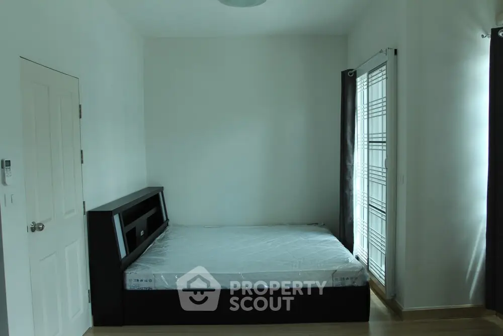 Spacious bedroom with modern bed and natural light from large window.