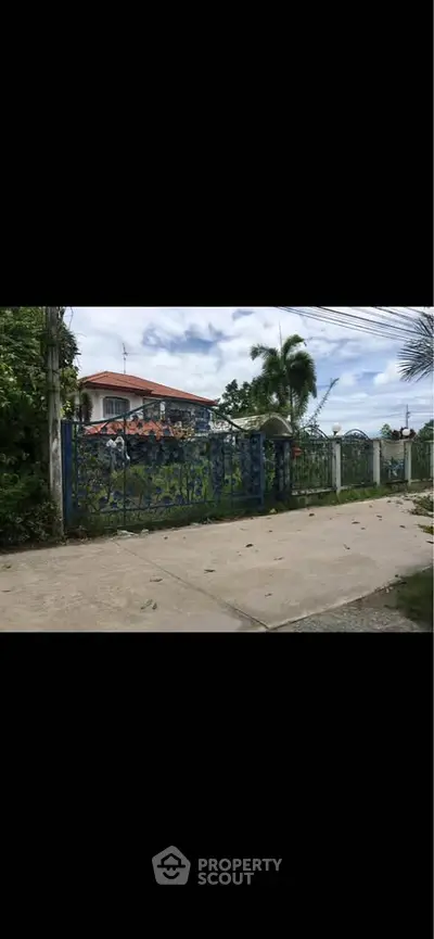 Charming gated property with lush greenery and spacious driveway, perfect for privacy and tranquility seekers.