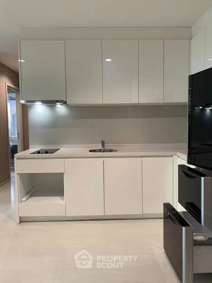 Modern kitchen with sleek white cabinets and built-in appliances in a contemporary apartment.