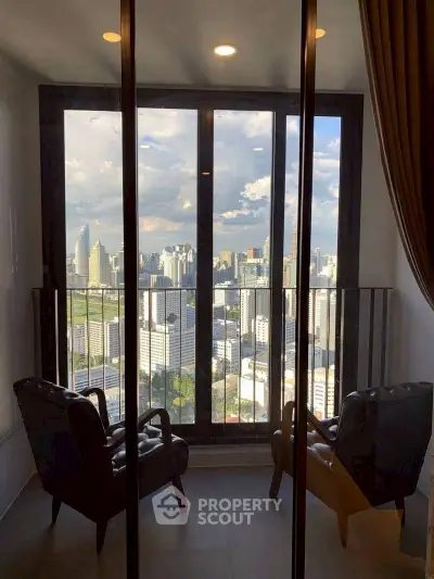 Stunning city view from a high-rise balcony with cozy seating area.