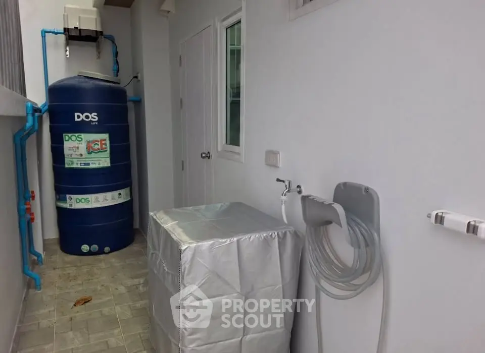 Outdoor utility area with water tank and covered washing machine in modern home.