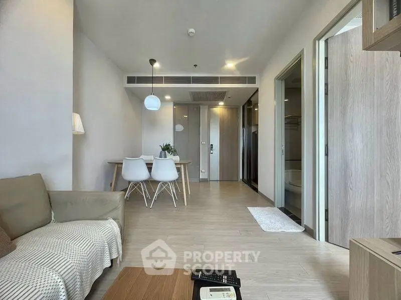 Modern living room with dining area, stylish furniture, and wooden flooring in a contemporary apartment.