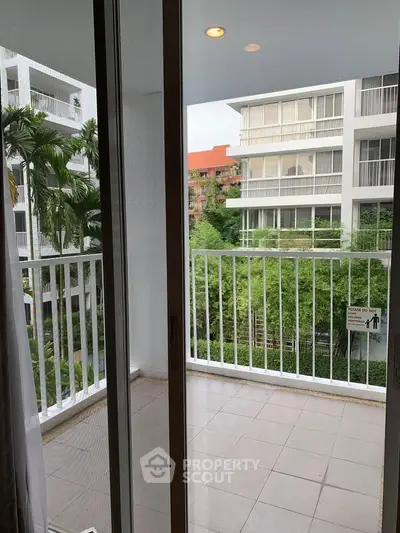 Spacious balcony with serene garden view in modern apartment complex.