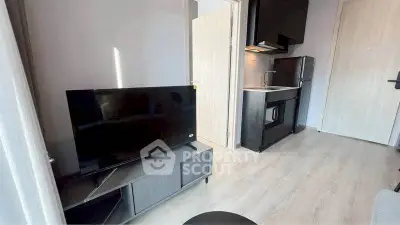 Modern compact living space with sleek kitchen and TV setup.