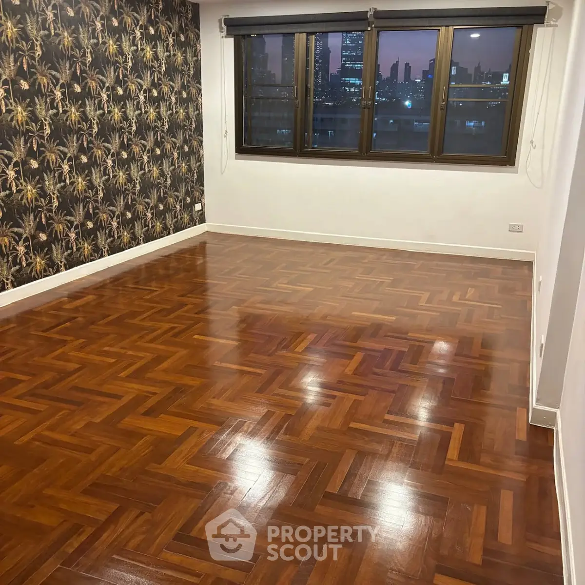 Spacious room with polished wooden floors and city view through large window.
