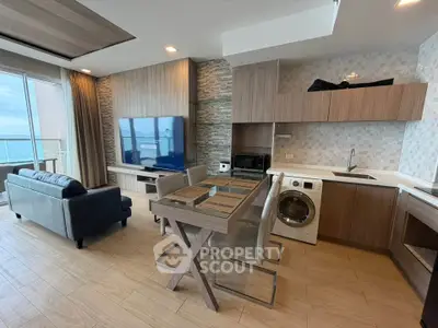 Modern open-plan living room with ocean view, featuring sleek kitchen and stylish furnishings.