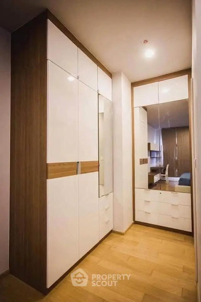 Modern walk-in closet with sleek white cabinetry and wooden accents