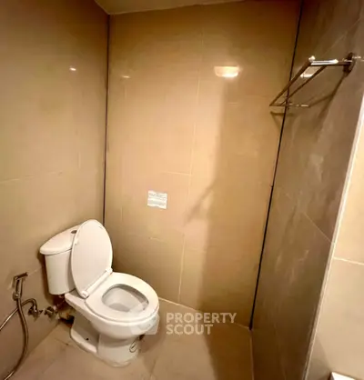 Modern bathroom with sleek beige tiles and white toilet in a minimalist design.