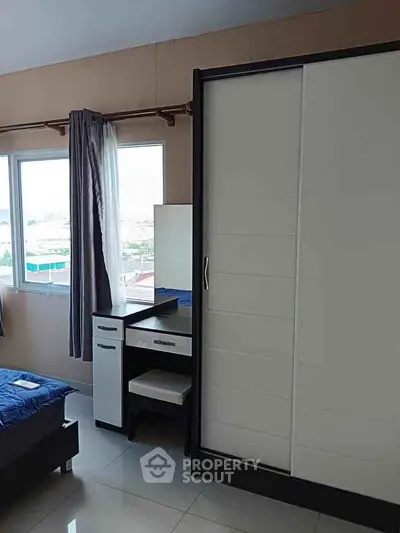 Modern bedroom with large wardrobe and vanity near window offering city views.