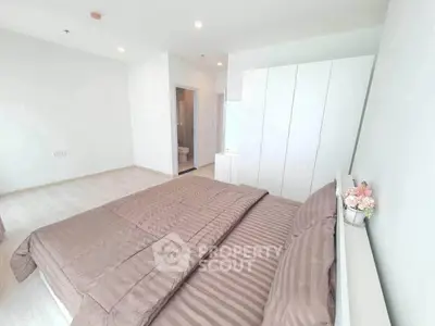 Spacious bedroom with modern decor and ample natural light, featuring a cozy bed and sleek wardrobe.