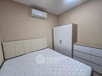 Cozy bedroom with air conditioning, modern wardrobe, and dresser in a minimalist design.