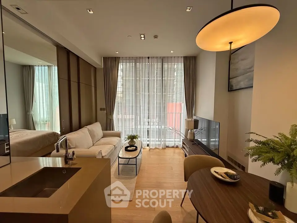 Modern living room with open kitchen, stylish decor, and natural light