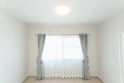 Bright and airy room with large window and elegant curtains, perfect for a cozy living space.