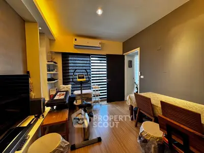 Cozy living room with exercise bike and dining area, featuring modern decor and warm lighting.