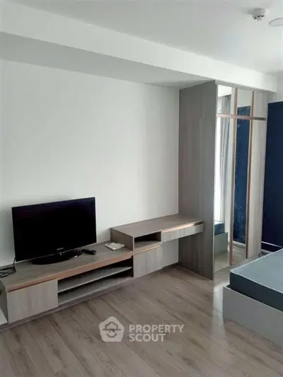 Modern bedroom with sleek wooden furniture and flat-screen TV, perfect for urban living.