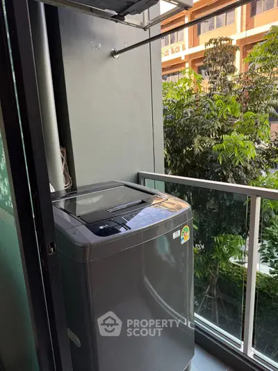 Modern balcony with washing machine and lush green view, perfect for urban living convenience.