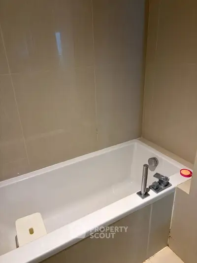 Modern bathroom with sleek bathtub and neutral tile design.