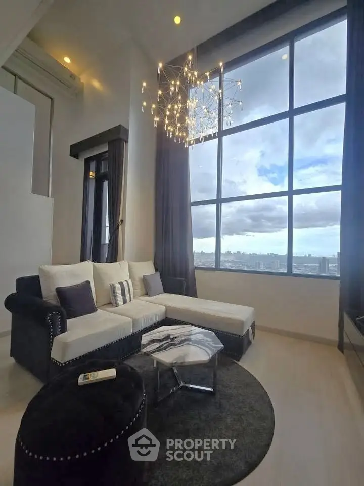 Luxurious high-ceiling living room with panoramic city view and elegant chandelier.