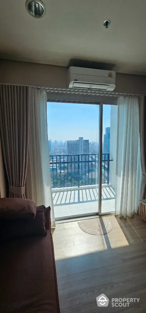 Modern living room with balcony and city view, featuring floor-to-ceiling windows and air conditioning.