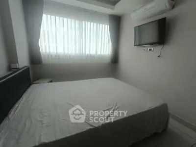 Cozy bedroom with natural light, air conditioning, and wall-mounted TV.