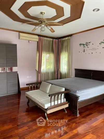 Spacious bedroom with elegant wooden flooring and stylish ceiling design