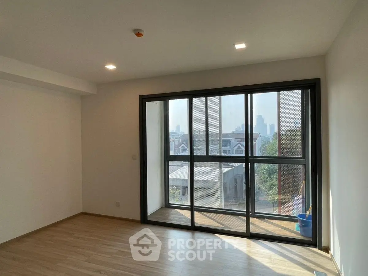 Spacious modern room with large windows and city view, perfect for urban living.