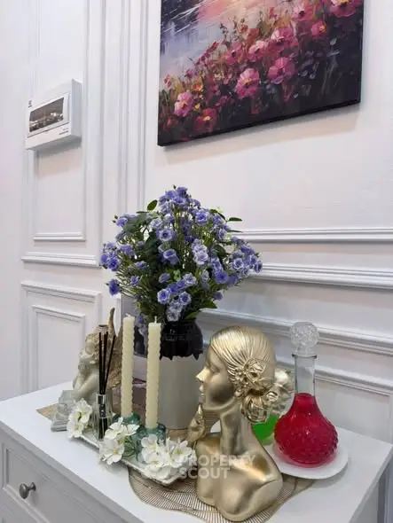 Elegant interior decor with floral arrangement and artistic accents on a white cabinet.