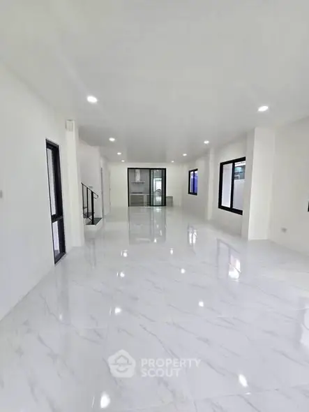 Spacious modern living room with sleek marble flooring and ample natural light.