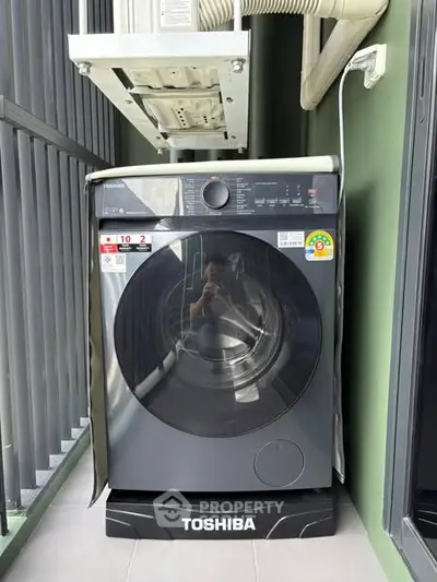 Modern Toshiba washing machine on a balcony with sleek design and energy efficiency.