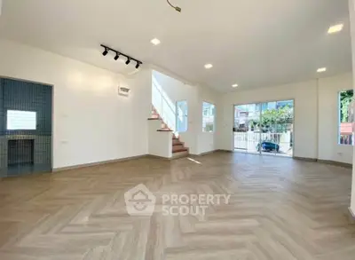 Spacious modern living room with herringbone flooring and large windows for natural light.