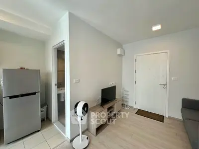 Modern living room with sleek furniture and open layout, featuring a compact kitchen and stylish decor.