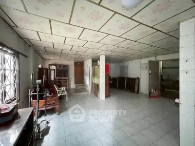 Spacious interior with tiled flooring and floral ceiling design, offering potential for renovation.