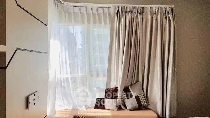 Cozy window nook with elegant curtains and decorative pillows in a bright room.