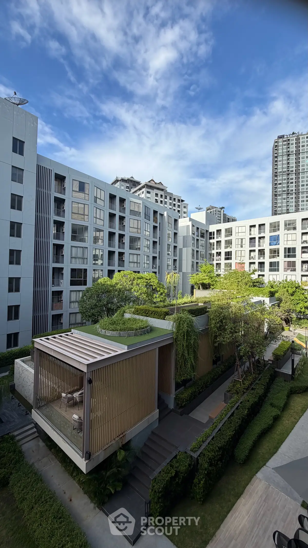Modern apartment complex with lush greenery and stylish outdoor seating area.