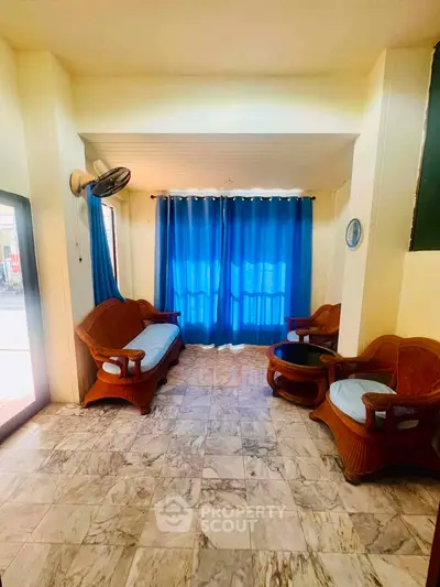 Charming living room with cozy wicker furniture and vibrant blue curtains, perfect for relaxation.