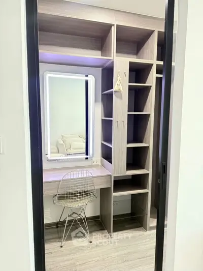 Modern walk-in closet with built-in shelves and illuminated mirror in stylish apartment.