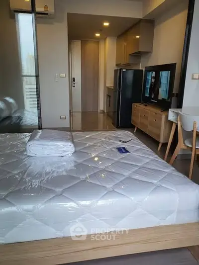Modern studio apartment with sleek kitchen and cozy living area, featuring a comfortable bed and stylish furniture.