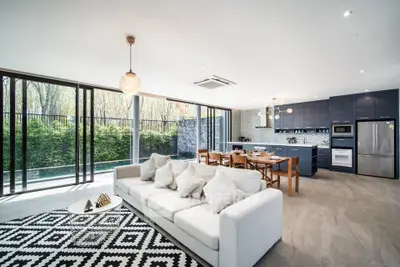 Luxurious open-plan living room with modern kitchen and pool view, featuring elegant decor and spacious design.