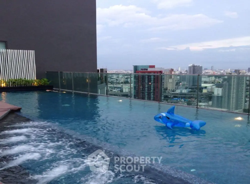 Stunning rooftop pool with city skyline view and playful inflatable dolphin.