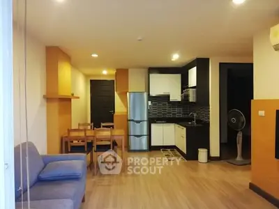 Modern open-plan living room with kitchen, featuring sleek design and cozy dining area.