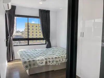Modern bedroom with large window and city view, featuring sleek white wardrobe and cozy bed.