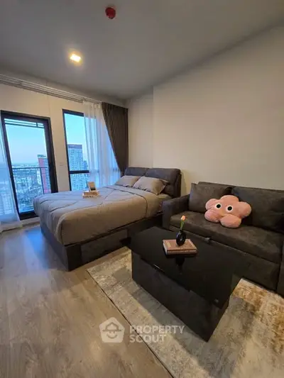 Modern bedroom with city view, featuring cozy bed and stylish sofa in a high-rise apartment.