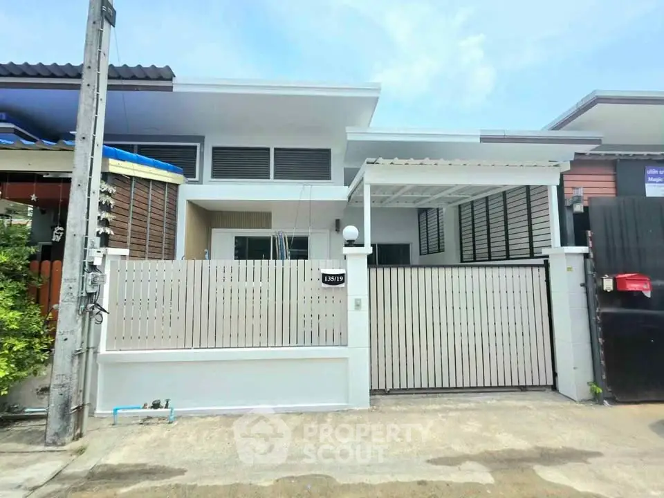 Modern single-story house with gated entrance and sleek design in a suburban neighborhood.