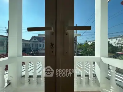 Charming balcony view with classic railing and sunny neighborhood backdrop.