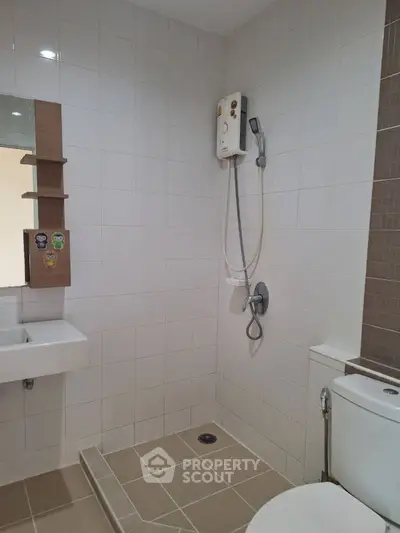 Modern bathroom with sleek design featuring a shower, sink, and toilet in a tiled setting.
