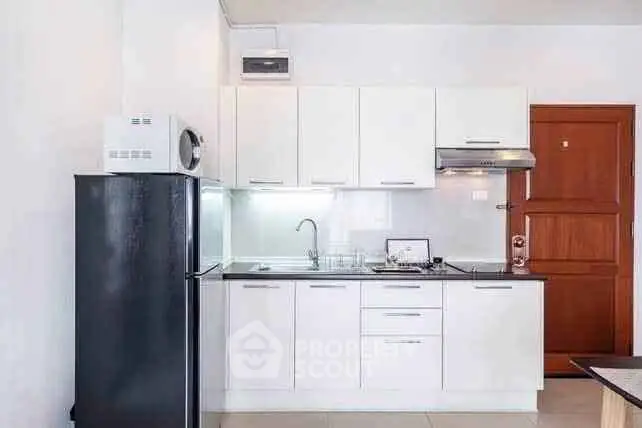 Modern kitchen with sleek white cabinets and black appliances in a compact layout.